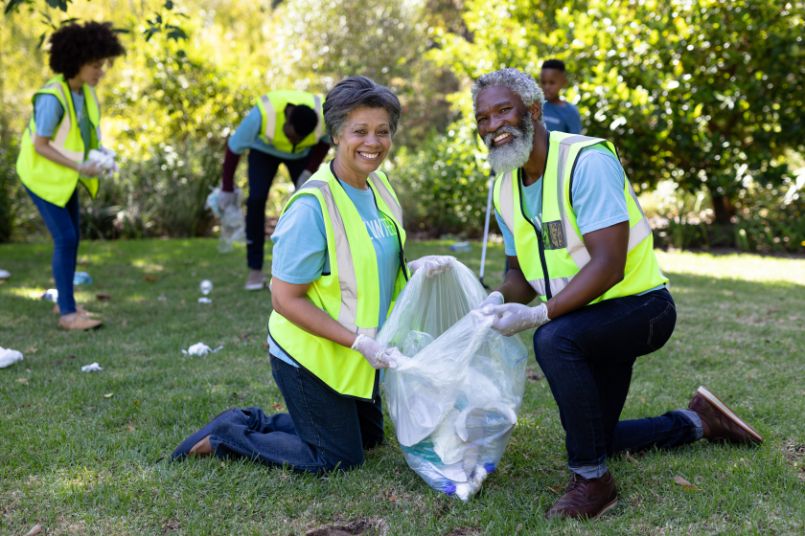 A senior man and woman volunteer to pick up litter at a local park.