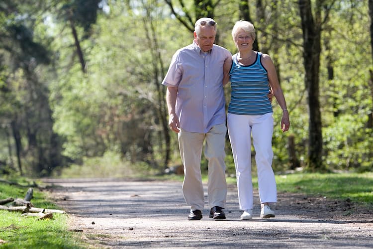 senior couple strolling through the park arm in arm