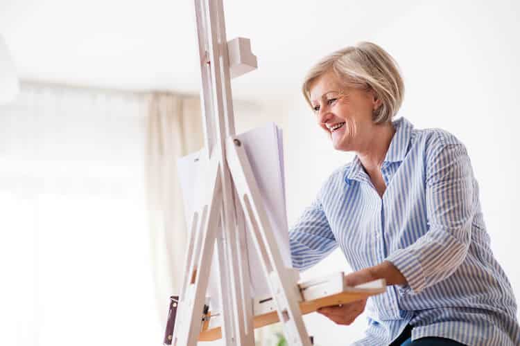 A happy senior woman painting.