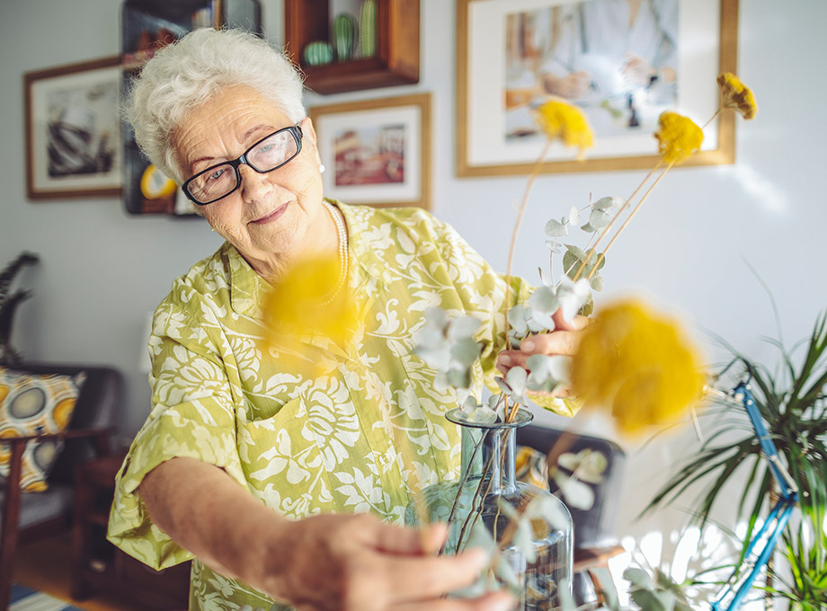 senior woman arranging flowers in vase