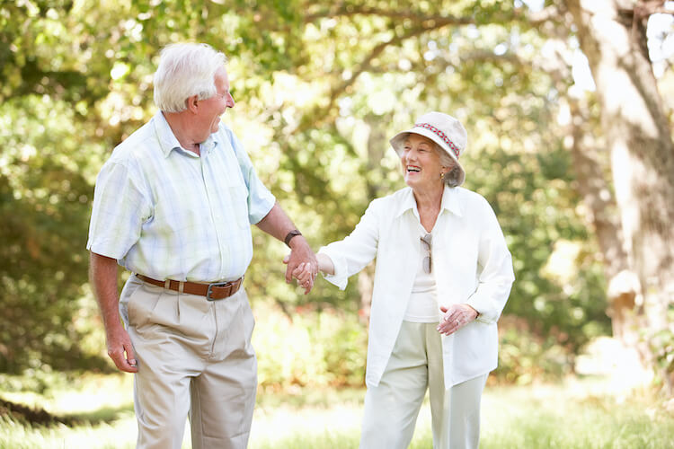 Senior couple walking in a park as a way to exercise and boost their immune health.