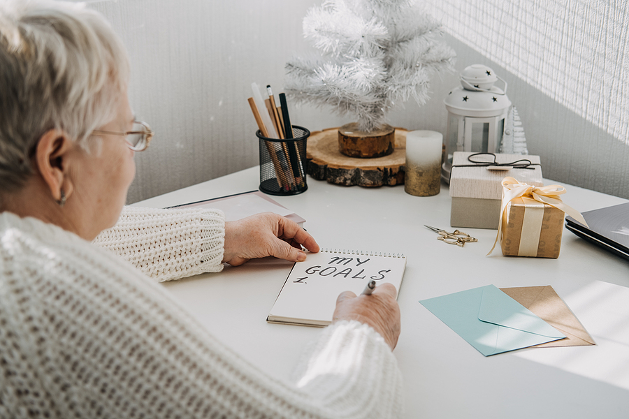 A senior woman sitting at a desk making new year resolution goals.