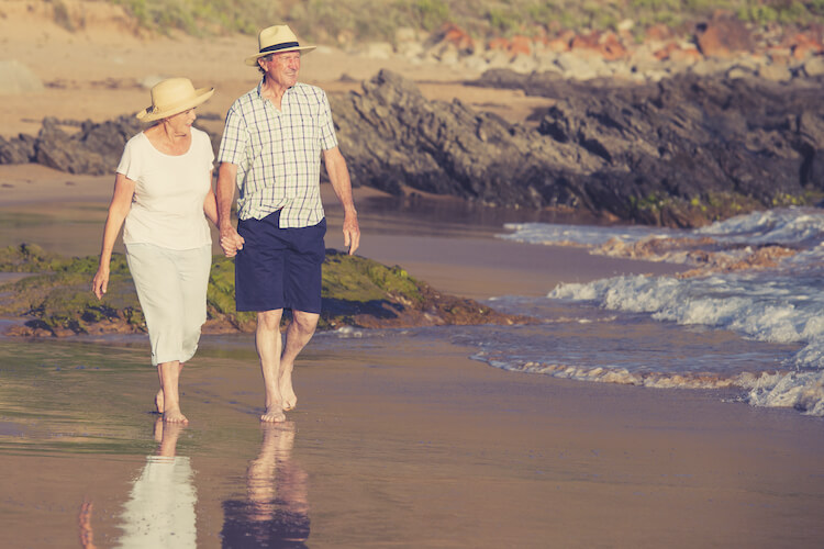 Senior couple enjoying retirement with a stroll on the beach.