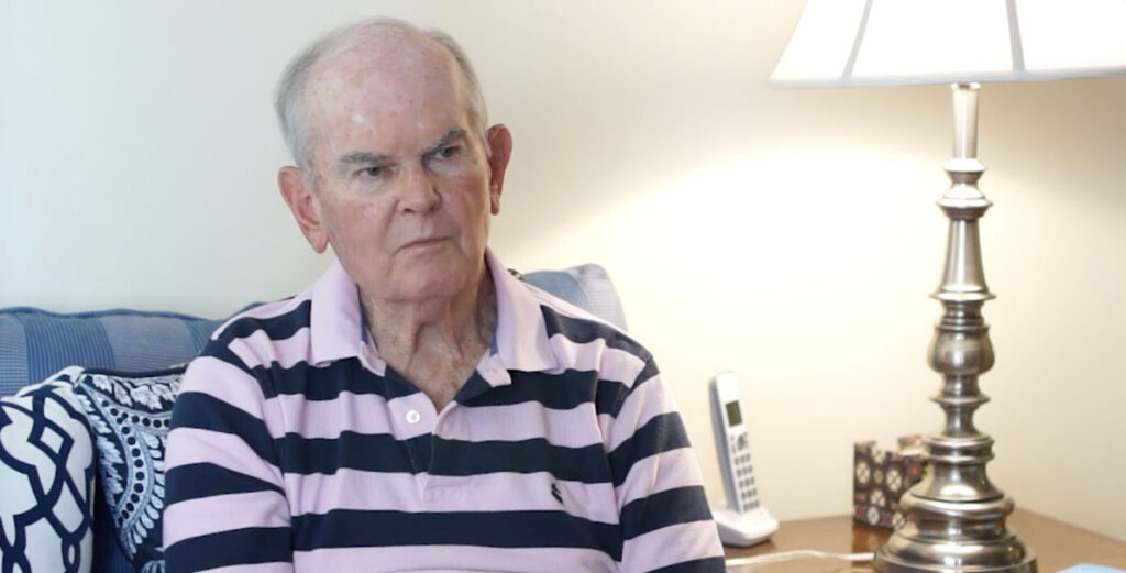 senior man in pink and blue striped shirt