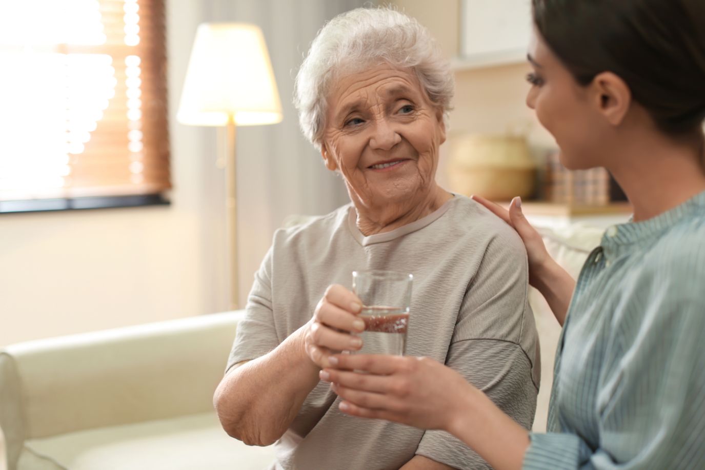 Senior woman receiving medication management assistance from a healthcare team member at a senior living community.