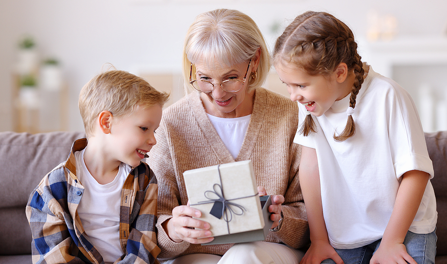 A senior woman opens a gift from her grandchildren.