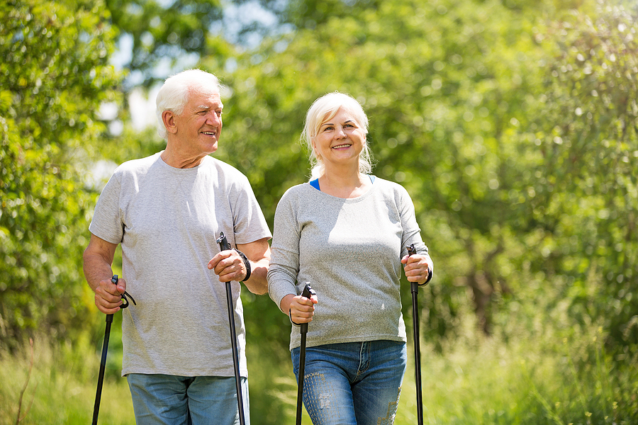 Senior couple nordic walking in park on a sunny Spring day