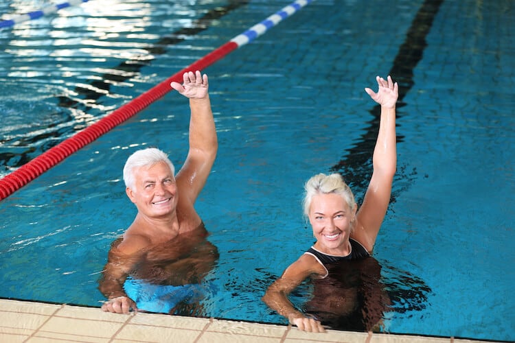Senior couple doing exercises in indoor swimming pool.